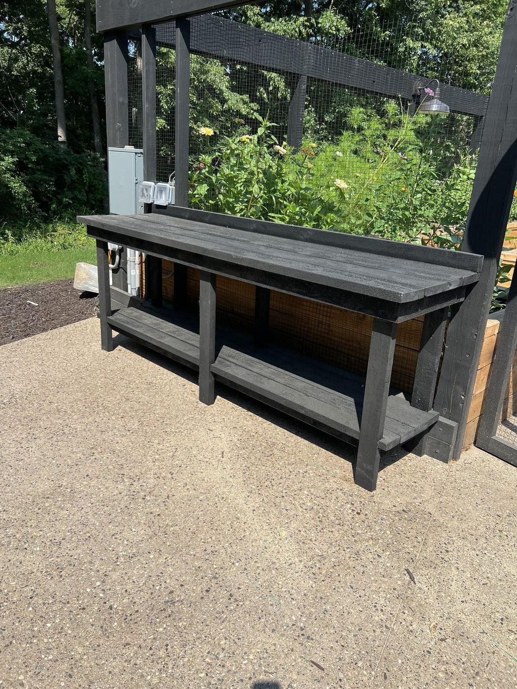 Blackened timber potting bench inside enclosed garden